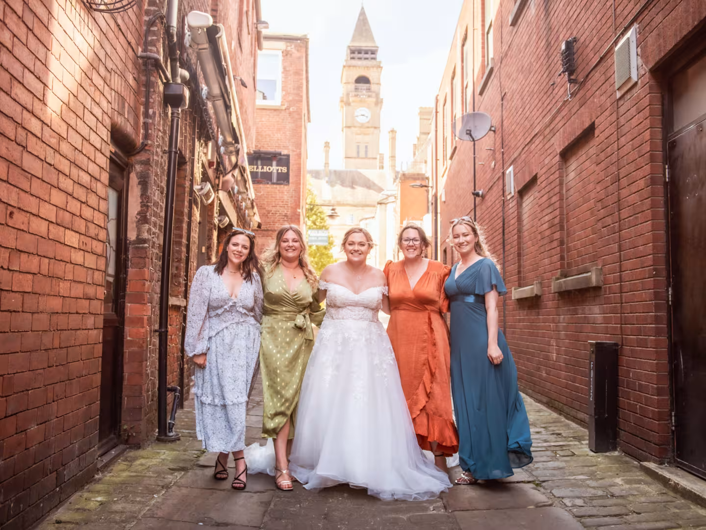 Bride and bridesmaids standing in an alley way