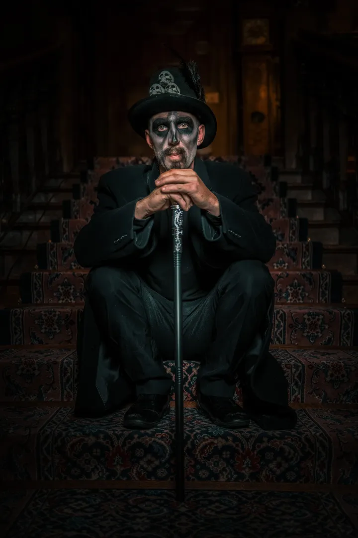 Voodoo man sitting on stairs with cane