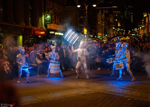 five drummers in a crowd covered in blue lights 