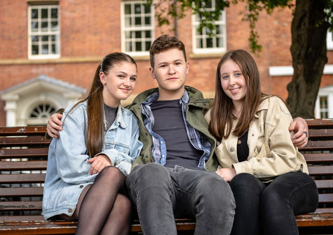 Three friends sitting on a bench in the park