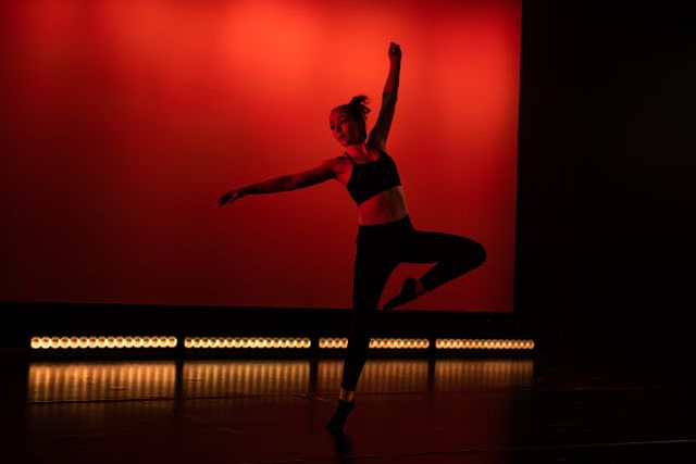 Dancer posing on stage under red light