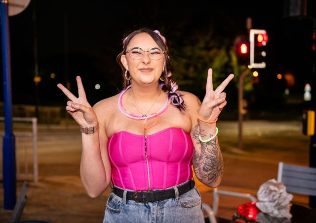 Women with pink top throwing up peace signs