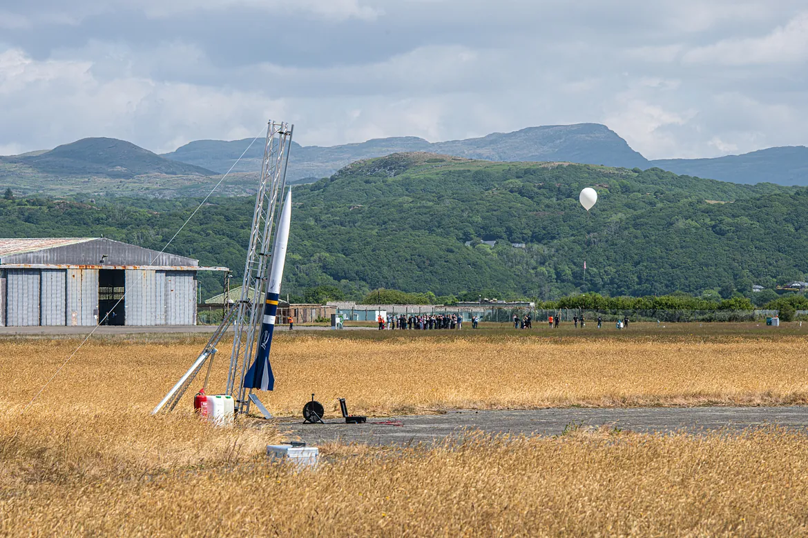 Landscape image showing a rocket to the left and a weather balloon to the right