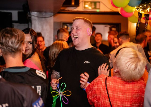 Man laughing in a crowd at a pub