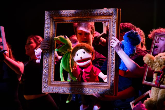 Crowd of hand puppets peering through a picture frame