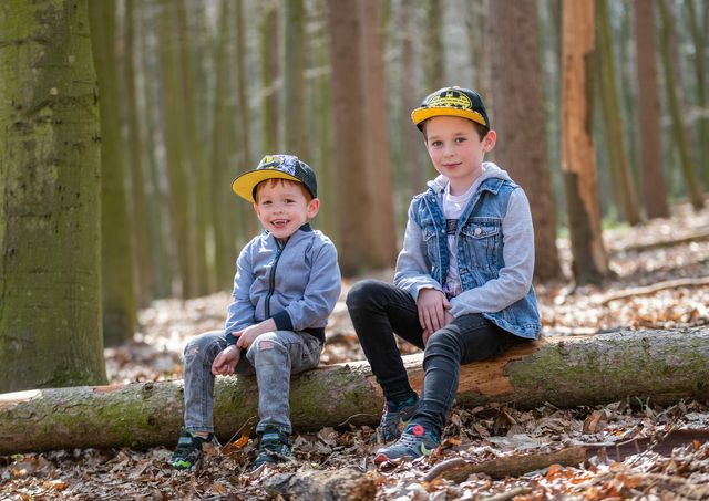 Two brothers sitting on a long in a forest