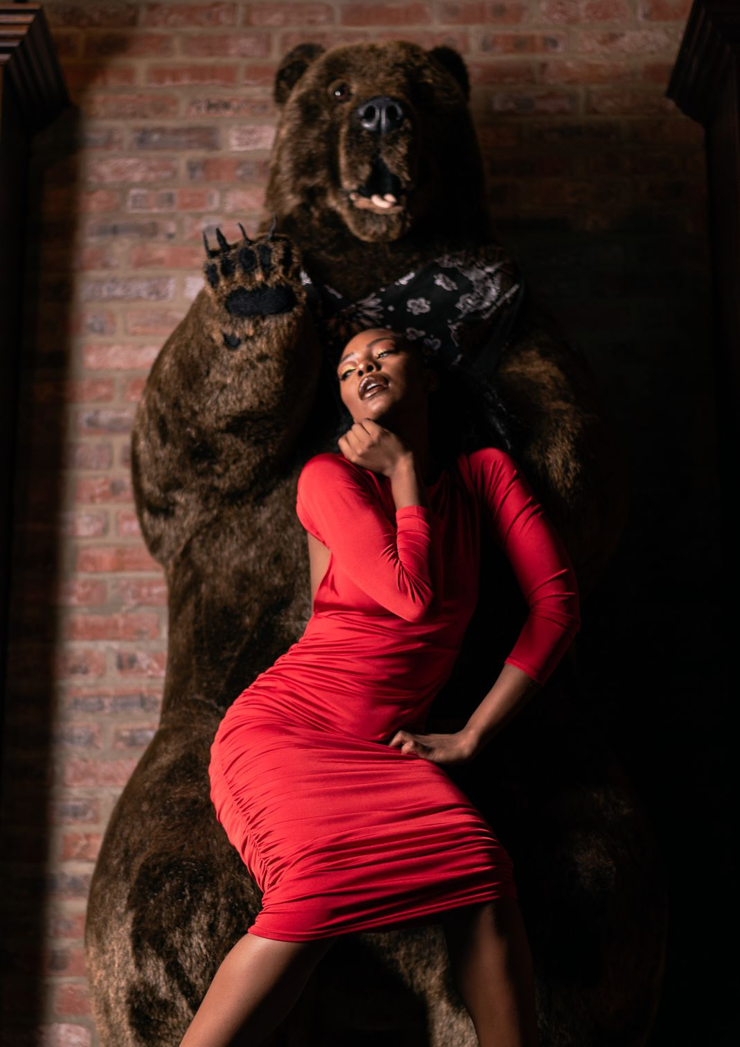 woman in red dress standing under a taxidermy bear