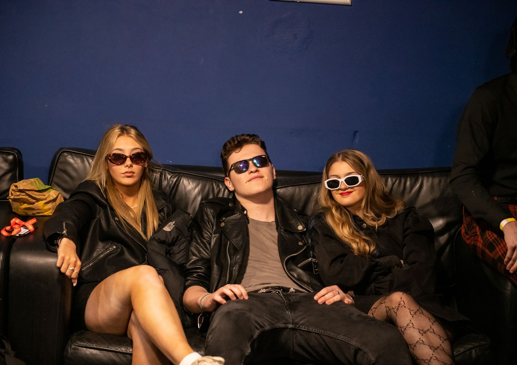 Three students with black sunglasses sitting on a sofa