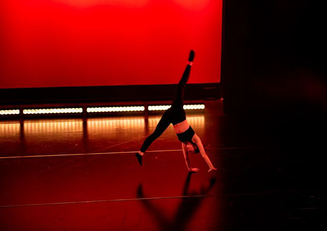 Dancer doing cartwheels in red light on stage 