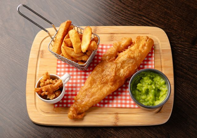 Fish chips scraps and peas on a platter