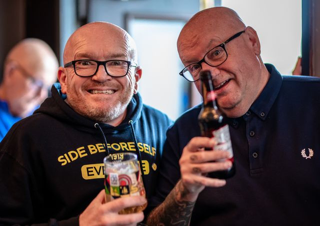 Two bald men having a drink together 