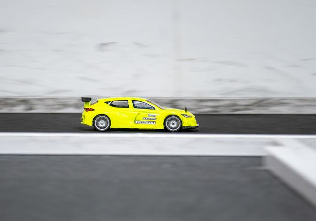 Yellow RC car going fast down a straight