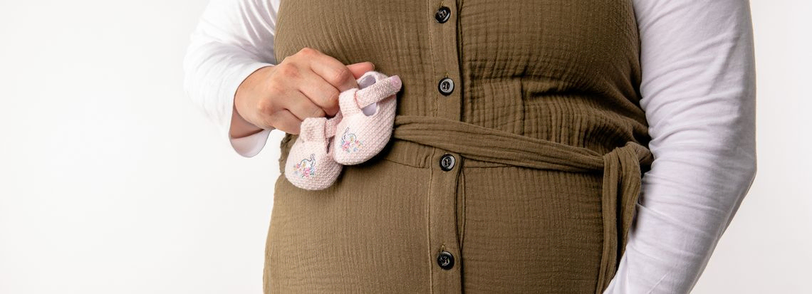 Pregnant lady holding baby shoes on bump