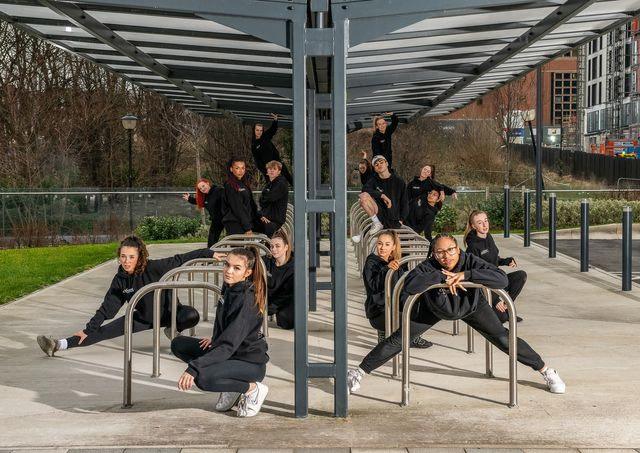 Dance crew posing under a bike shed
