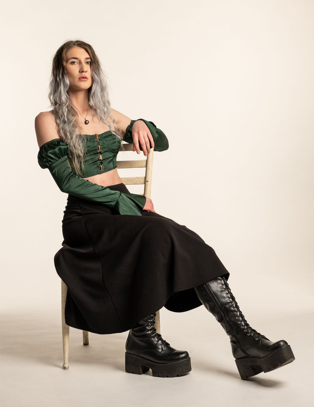 Woman in green with black boot sitting on a chair